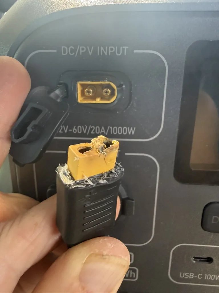 The melted connector held next to the DC/PV input port on the power station, showing the charred plastic