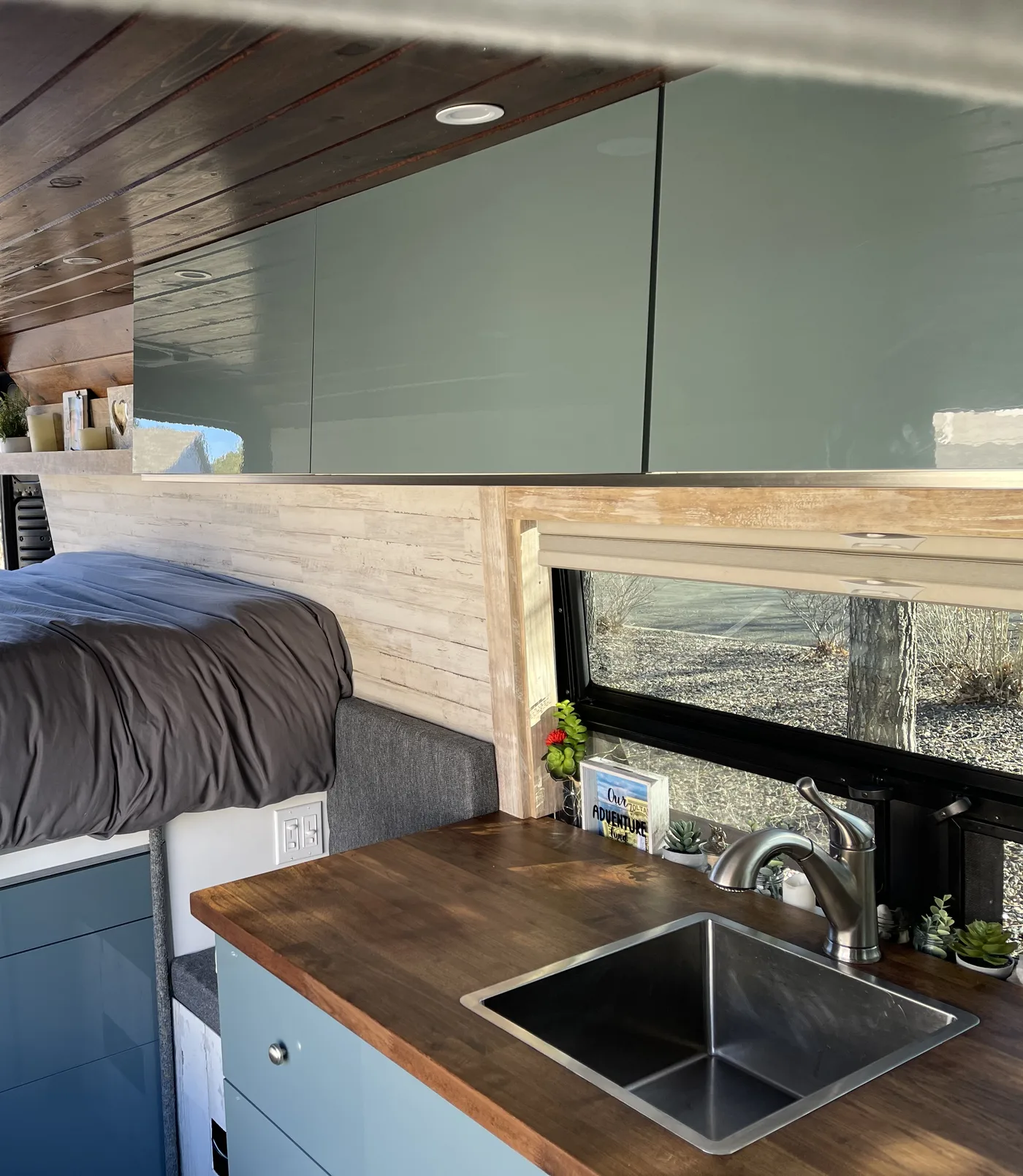 The galley in our ProMaster: three overhead cupboards, the butcher block counter with the sink, and the drawers under the bed