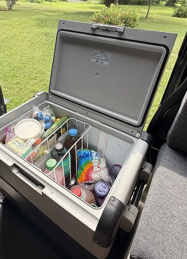 Our Dometic CFX 65DZ chest fridge open and packed with food and drinks, the divider basket sitting on top