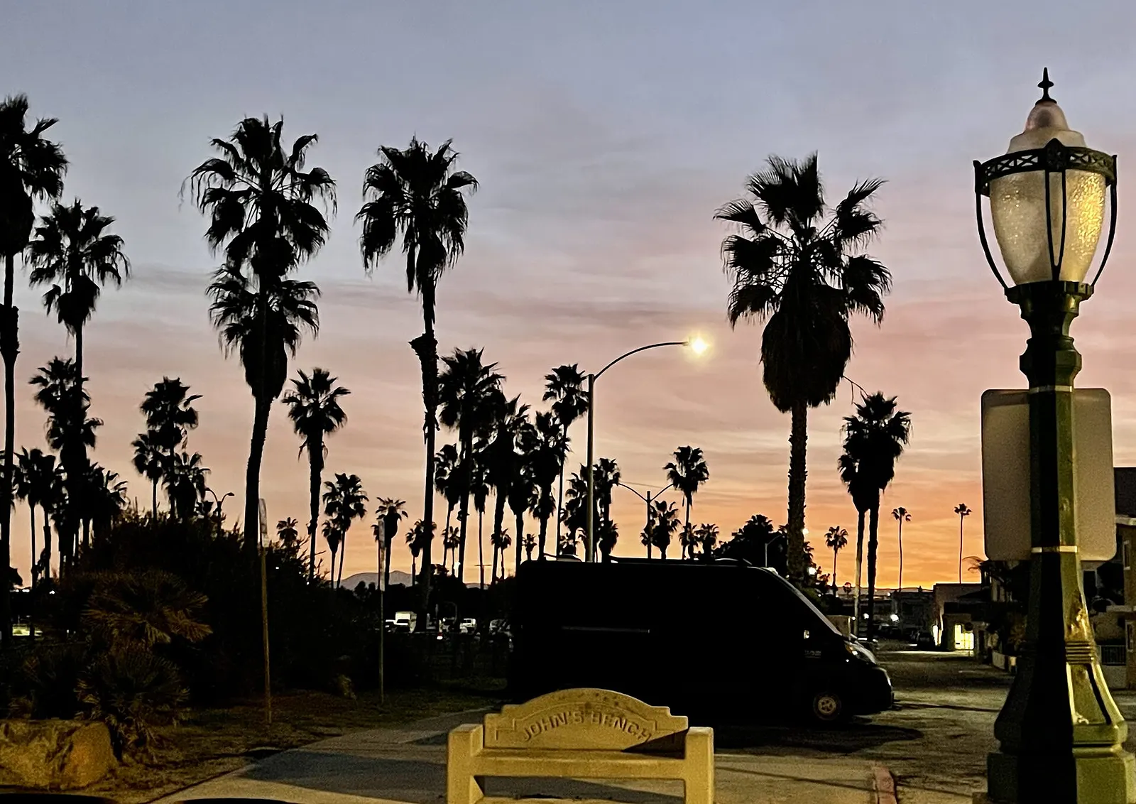 The van parked at dusk under palms, lights coming on